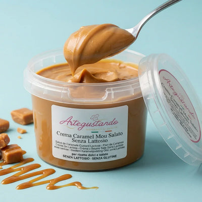 Crema caramel mou salato senza lattosio in barattolo, cucchiaio e caramello su sfondo azzurro
