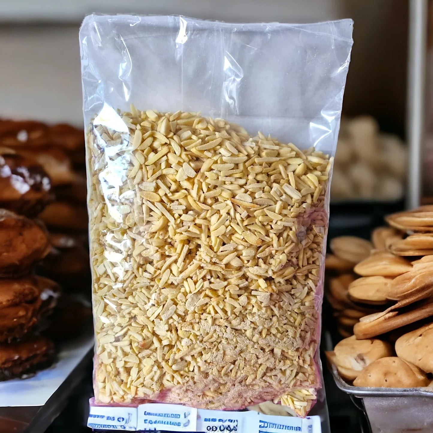 Sacchetto trasparente di mandorle affettate per pasticceria, tra dolci artigianali.