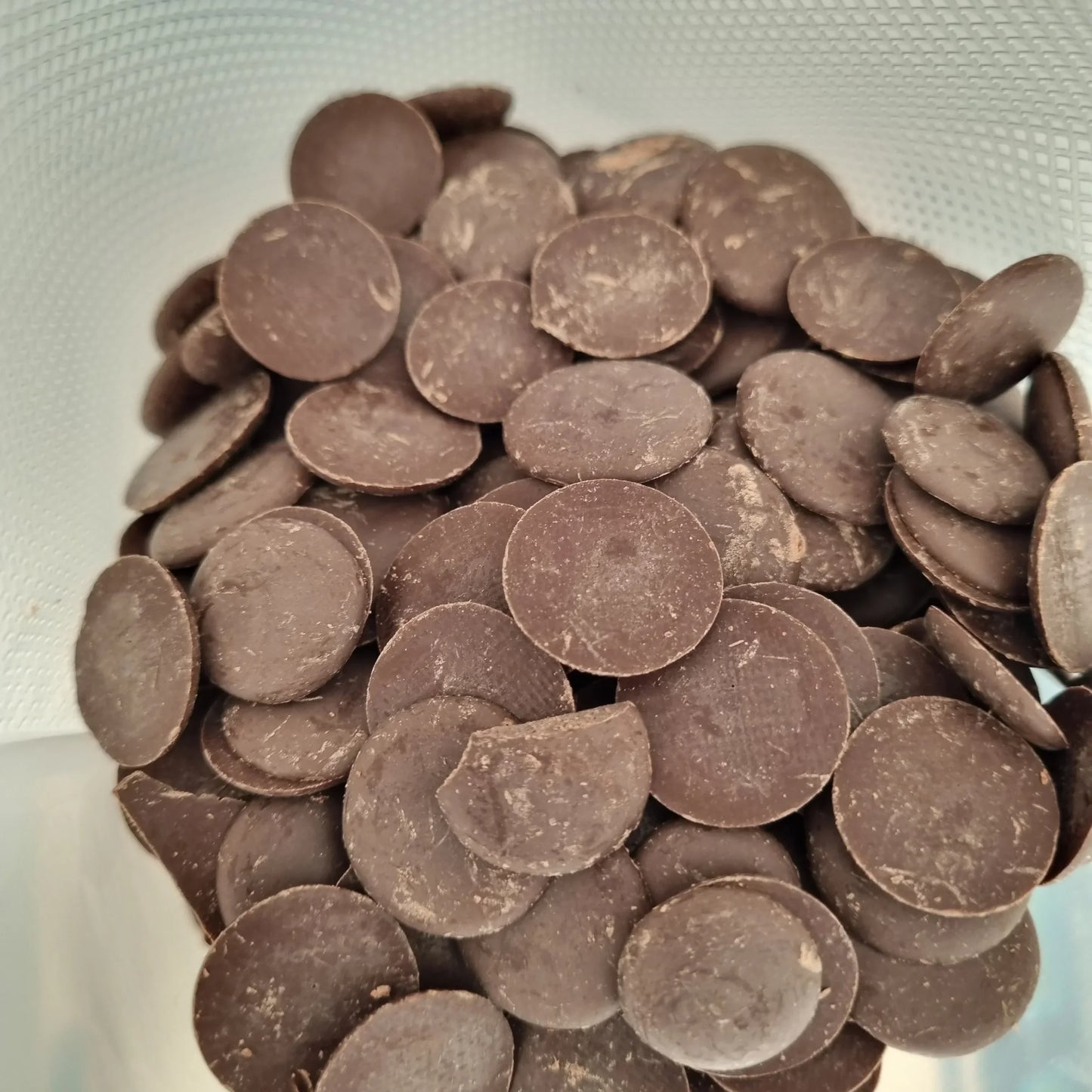 Gocce di cioccolato fondente in una busta, ingredienti per pasticceria e gelato artigianale.