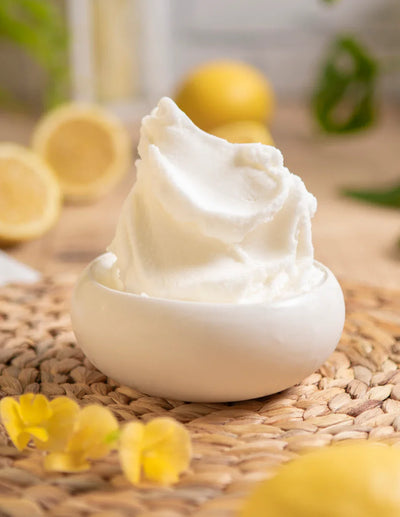 Gelato al limone cremoso in ciotola bianca con limoni freschi sullo sfondo, ingredienti per pasticceria.