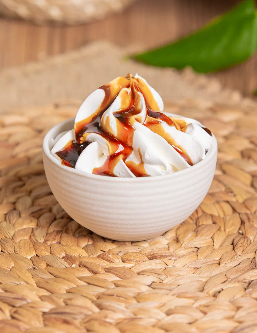 Crema gelato artigianale con salsa al caramello in ciotola bianca su tovaglietta intrecciata