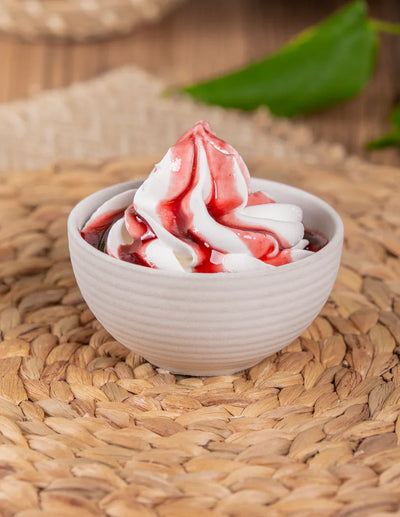 Frozen yogurt con salsa ai frutti di bosco in ciotola bianca su fondo intrecciato naturale.