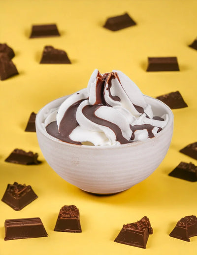 Ciotola di gelato alla panna con topping al cacao e pezzi di cioccolato su sfondo giallo