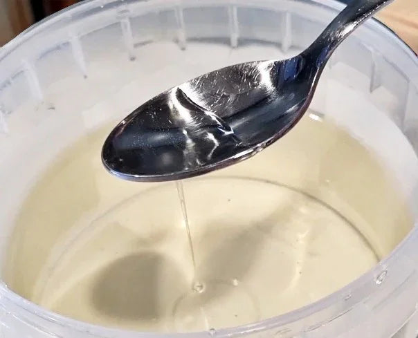 Cremosa pasta di nocciola chiara in un contenitore, versata con un cucchiaio