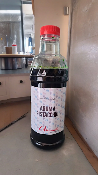 Bottiglia di aroma pistacchio per gelato e pasticceria su piano cucina, tappo rosso.