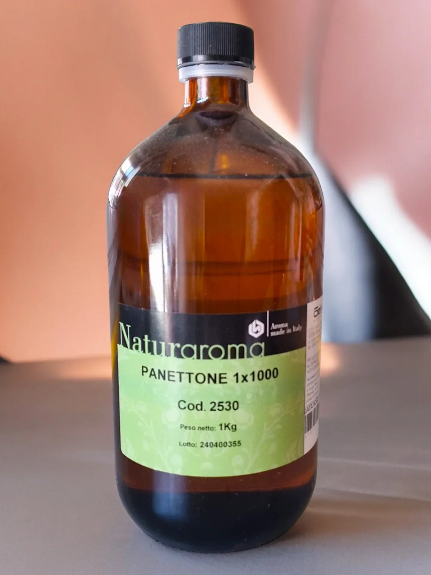 Bottiglia di aroma panettone per pasticceria da 1 kg Naturaroma su tavolo, etichetta verde visibile.