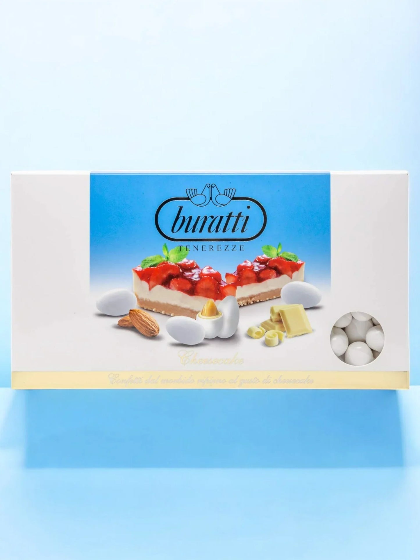 Scatola di confetti Buratti gusto cheesecake con mandorle, cioccolato bianco e fragole su sfondo azzurro.