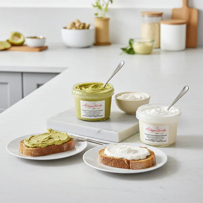 Crema di pistacchio senza lattosio e crema al cocco senza lattosio spalmate su fette di pane, vasetti su tavolo da cucina.