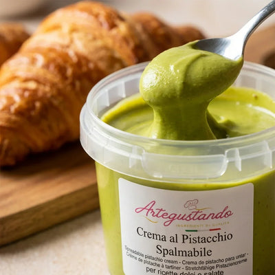 Crema al pistacchio spalmabile in vasetto con cucchiaio, croissant sullo sfondo