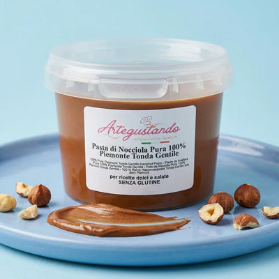 Vasetto di pasta di nocciola pura Piemonte Tonda Gentile su piatto azzurro con nocciole