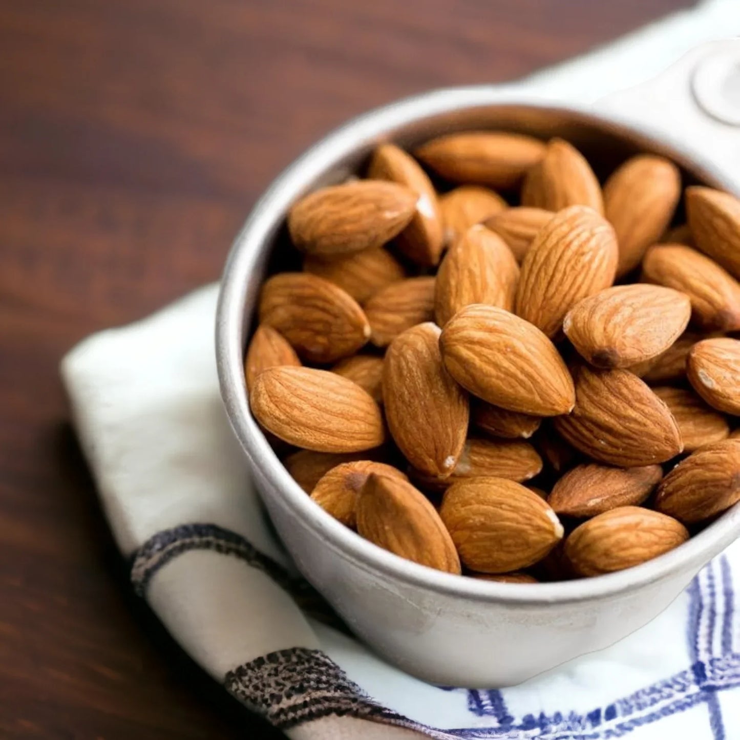 Mandorle sgusciate intere in ciotola su tovagliolo, ingredienti per dolci e pasticceria