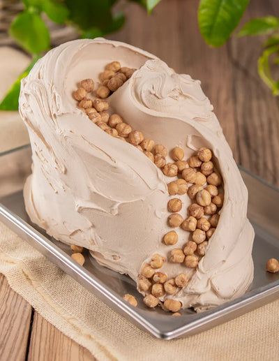 Gelato alla nocciola artigianale con nocciole intere su vassoio, ingrediente per pasticceria
