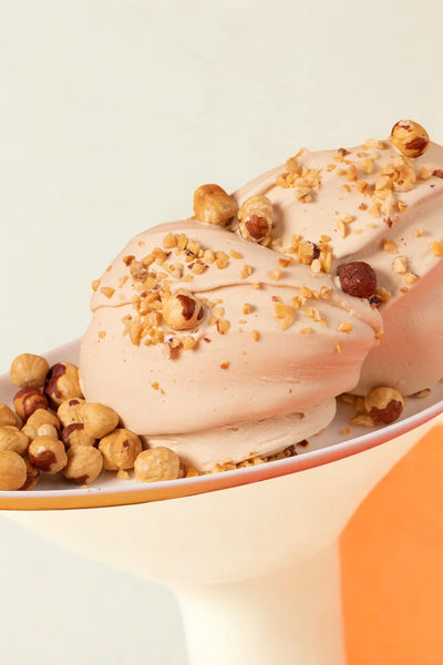 Gelato alla nocciola cremoso decorato con nocciole tostate e granella, dessert artigianale italiano.