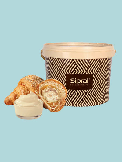 Secchiello di crema di nocciola bianca per pasticceria con croissant ripieni e vasetto.