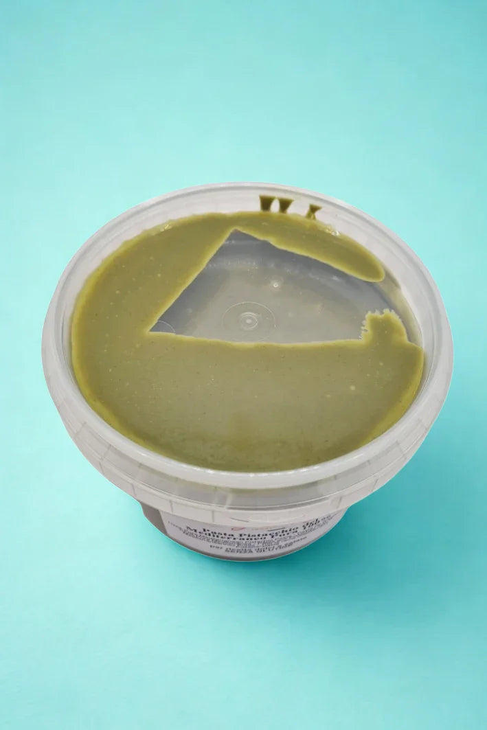 Vasetto di pasta di pistacchio mediterraneo per gelato e dolci su sfondo azzurro