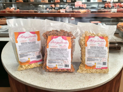 Tre confezioni di mandorle italiane di alta qualità esposte su banco pasticceria.
