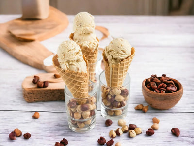 Gelato artigianale alla nocciola in coni wafer, su tavolo con nocciole intere