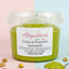 Crema al pistacchio spalmabile in vasetto trasparente con pistacchi e cucchiaio in primo piano.