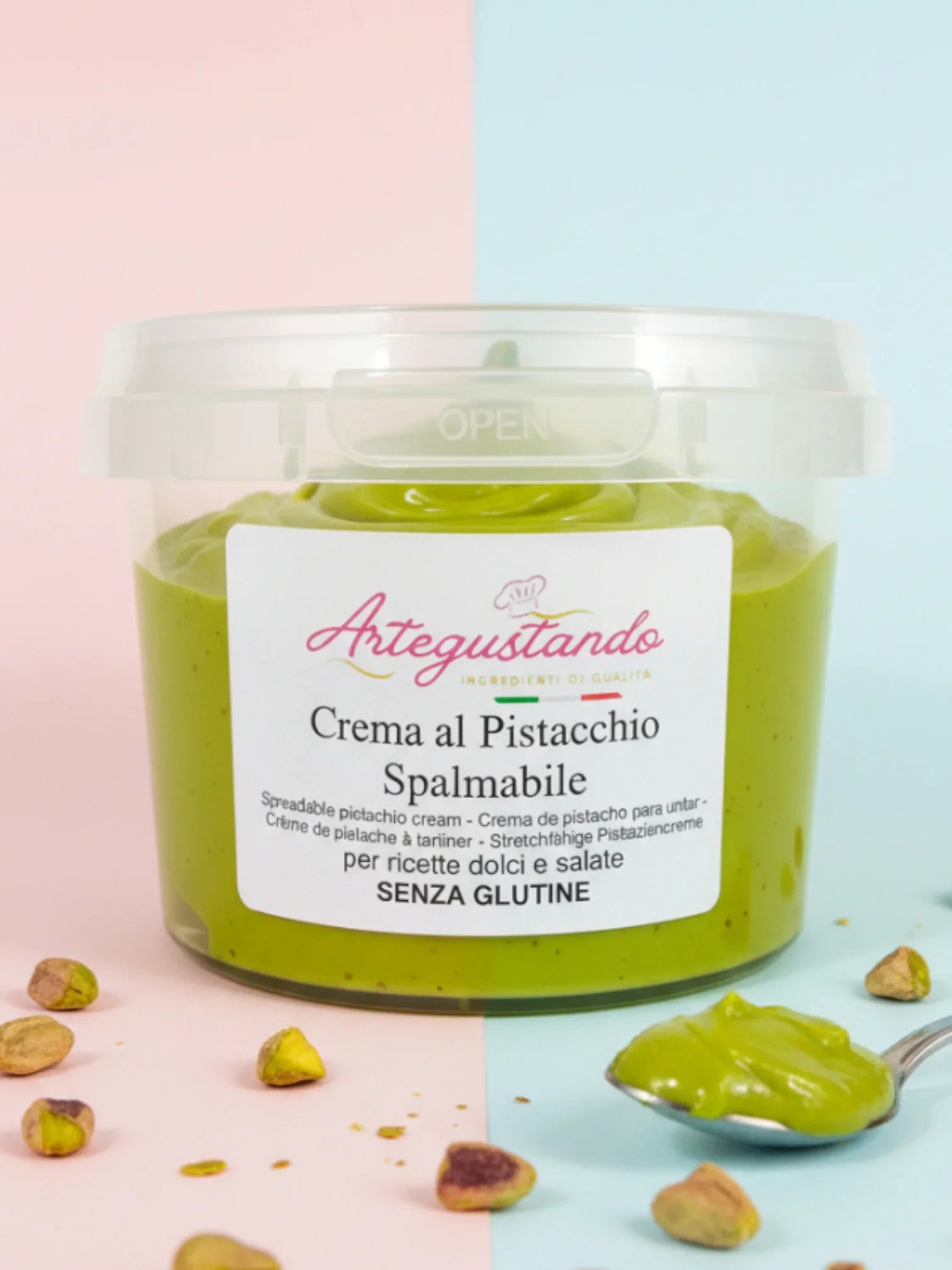 Crema al pistacchio spalmabile in vasetto trasparente con pistacchi e cucchiaio in primo piano.