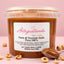 Barattolo di pasta di nocciola italiana pura 100% senza glutine, con nocciole e cucchiaio su sfondo rosa.