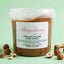 Vasetto di pasta di nocciola pura italiana senza glutine con nocciole intere e sgusciate su fondo verde.